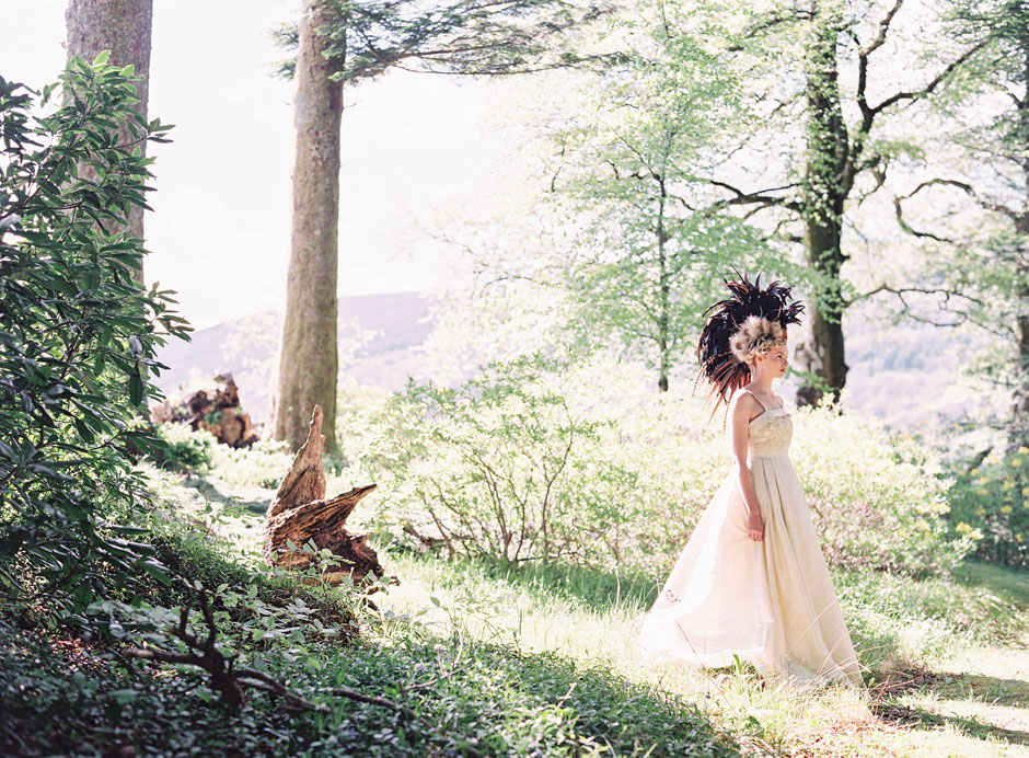 Editorial in Scotland with a girl in a large feather headpiece in the woodland